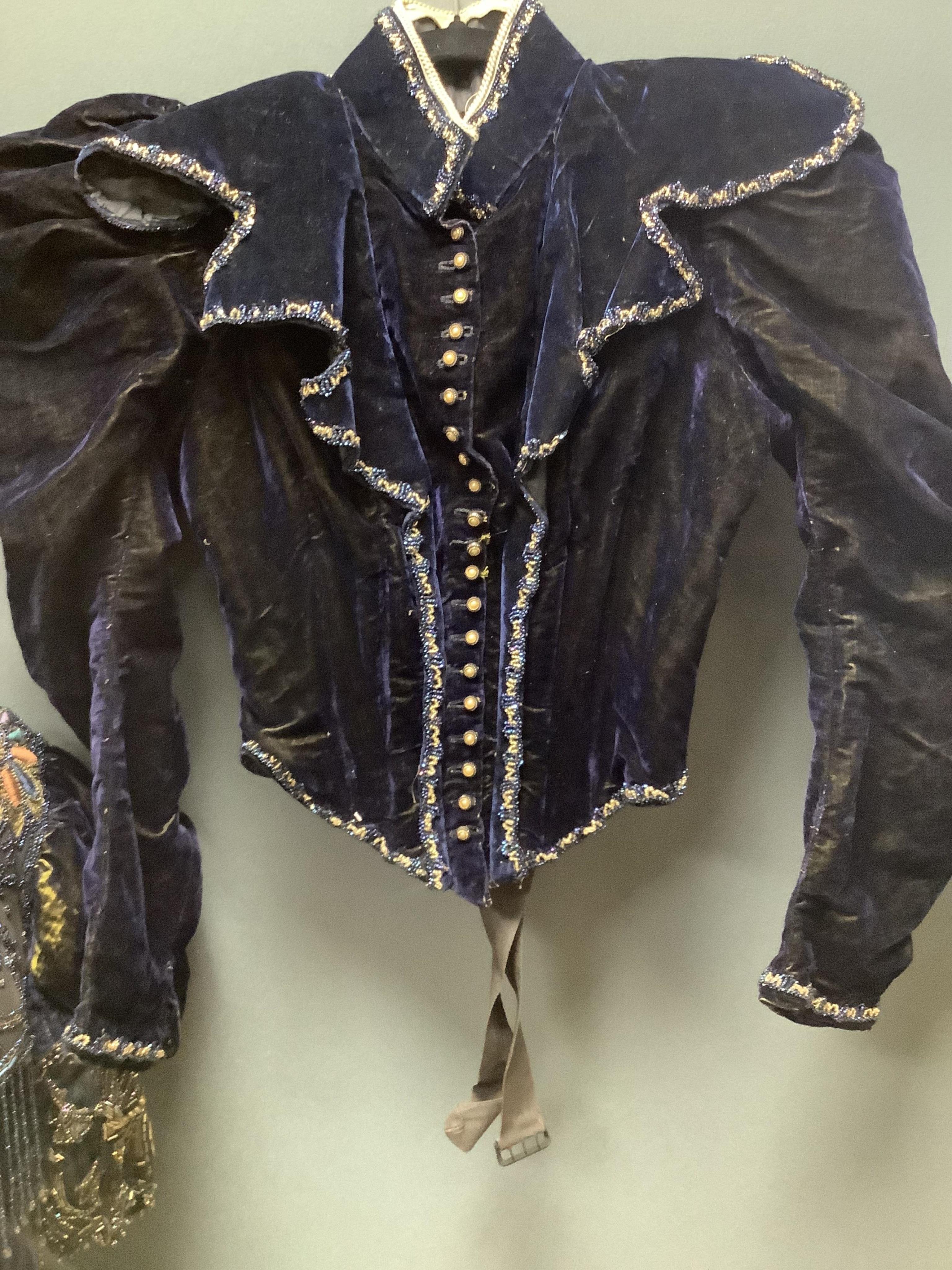 A 19th century ladies silk velvet matching long sleeved jacket/bodice, and skirt, together with another matching short sleeved bead worked bodice and white feather headdress.(4). Cape 106cm long. Condition - Both bodices